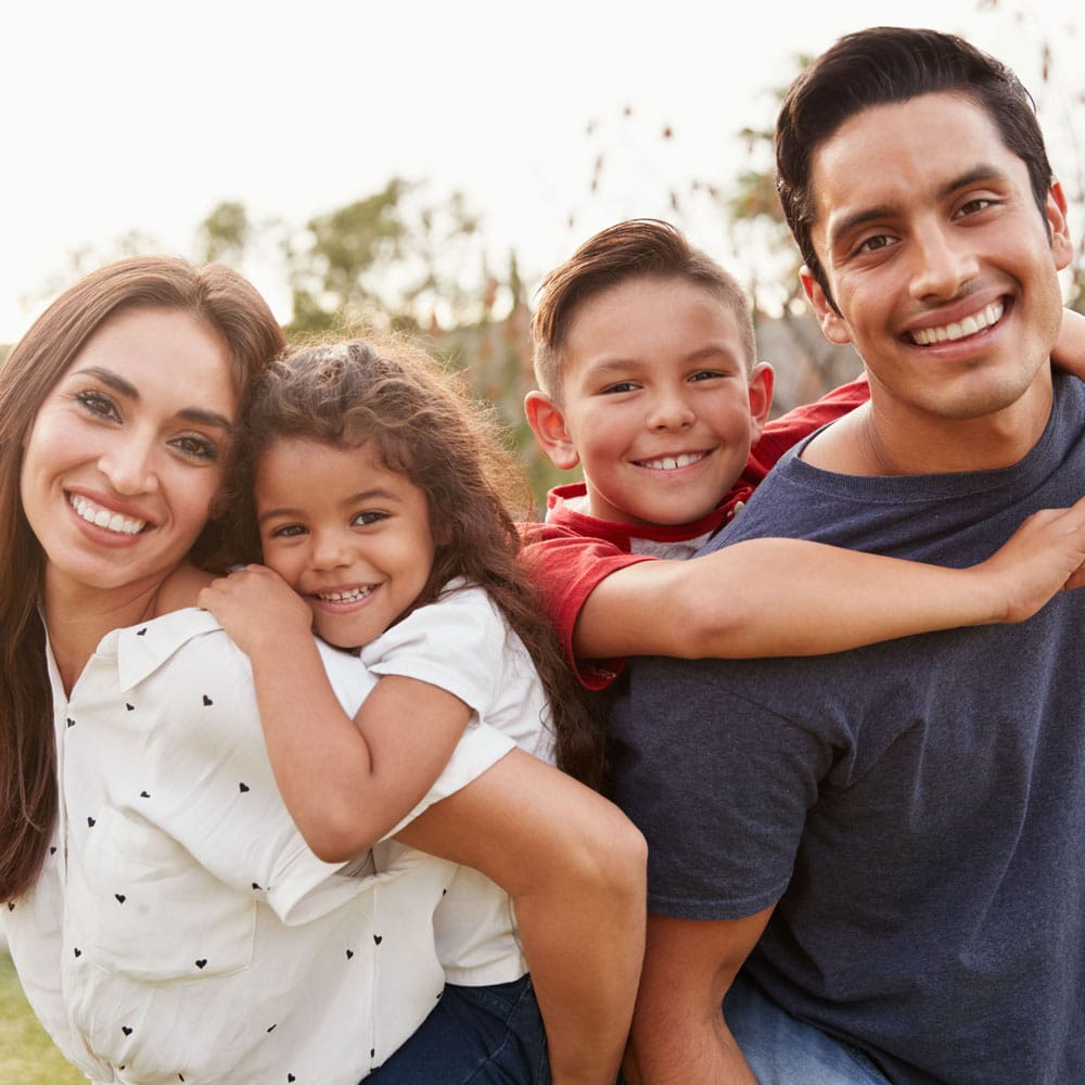 Portrait of Hispanic Family Smiling in the Camera and Their Kids Hugging them from Behind after visiting Joseph LaPonzina Orthodontics