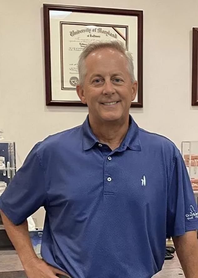 Middle-aged man in blue polo shirt smiling in orthodontic office setting.