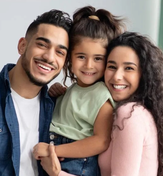 Happy family of three smiling together indoors in casual clothing.