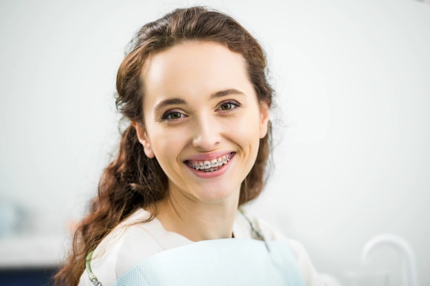 Young woman smiling at camera in white shirt, professional headshot for orthodontics practice.