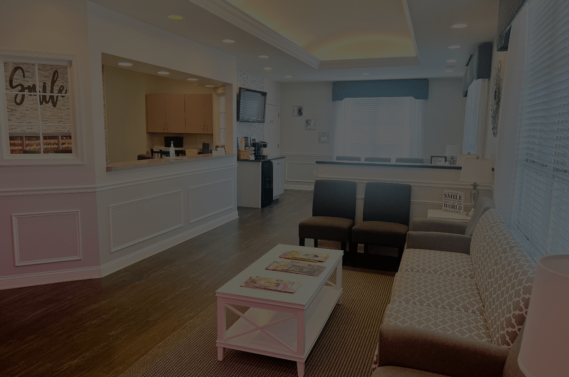 Modern orthodontic office waiting room with reception desk, seating, and dental treatment area visible.