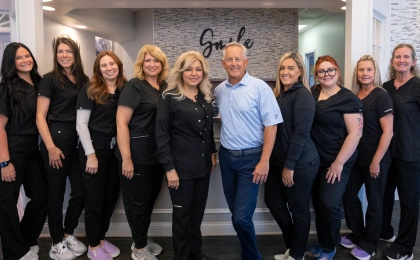 Dr. LaPonzina and female team members in black uniforms pose together in orthodontic office.