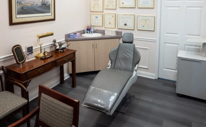 Modern orthodontic treatment room with dental chair, desk, and equipment in professional clinical setting.